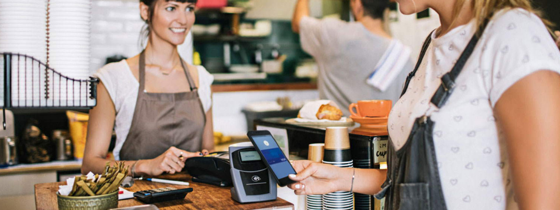 women in coffee shop paying contactless