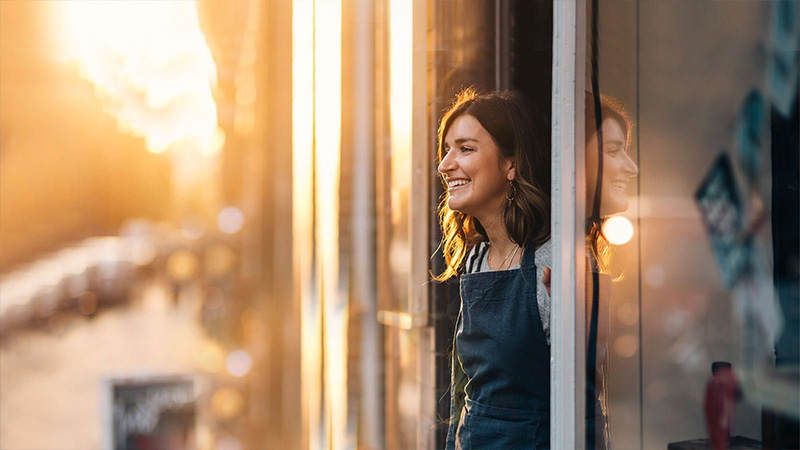 woman in shop doorway smiling 