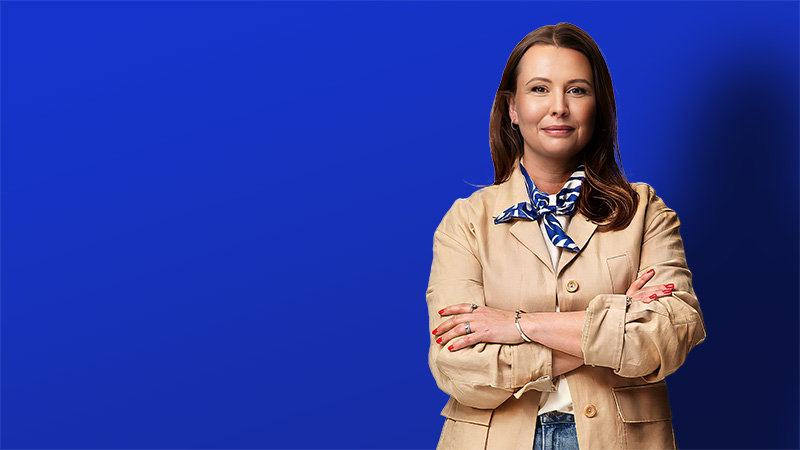 woman standing cross armed in front of blue background